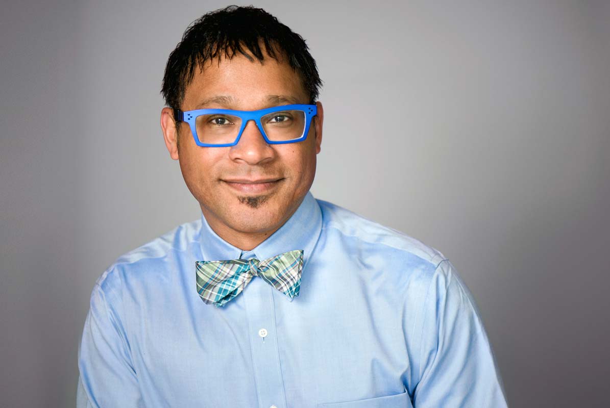headshot of a man wearing blue glasses