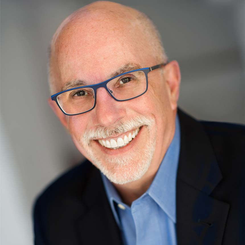 Shows a professional business headshot of a man with a gray beard, glasses, smiling