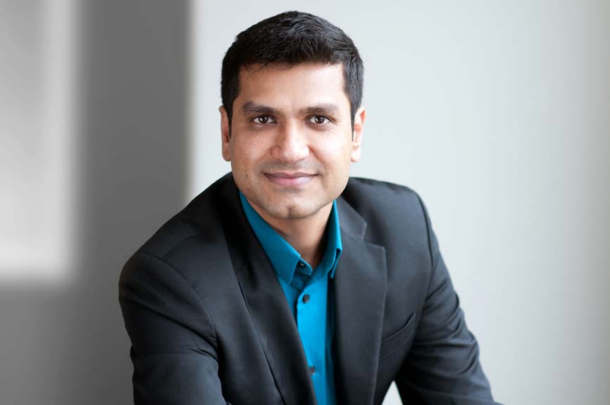 Shows a professional business headshot of a man, casual, landscape, light ambient background